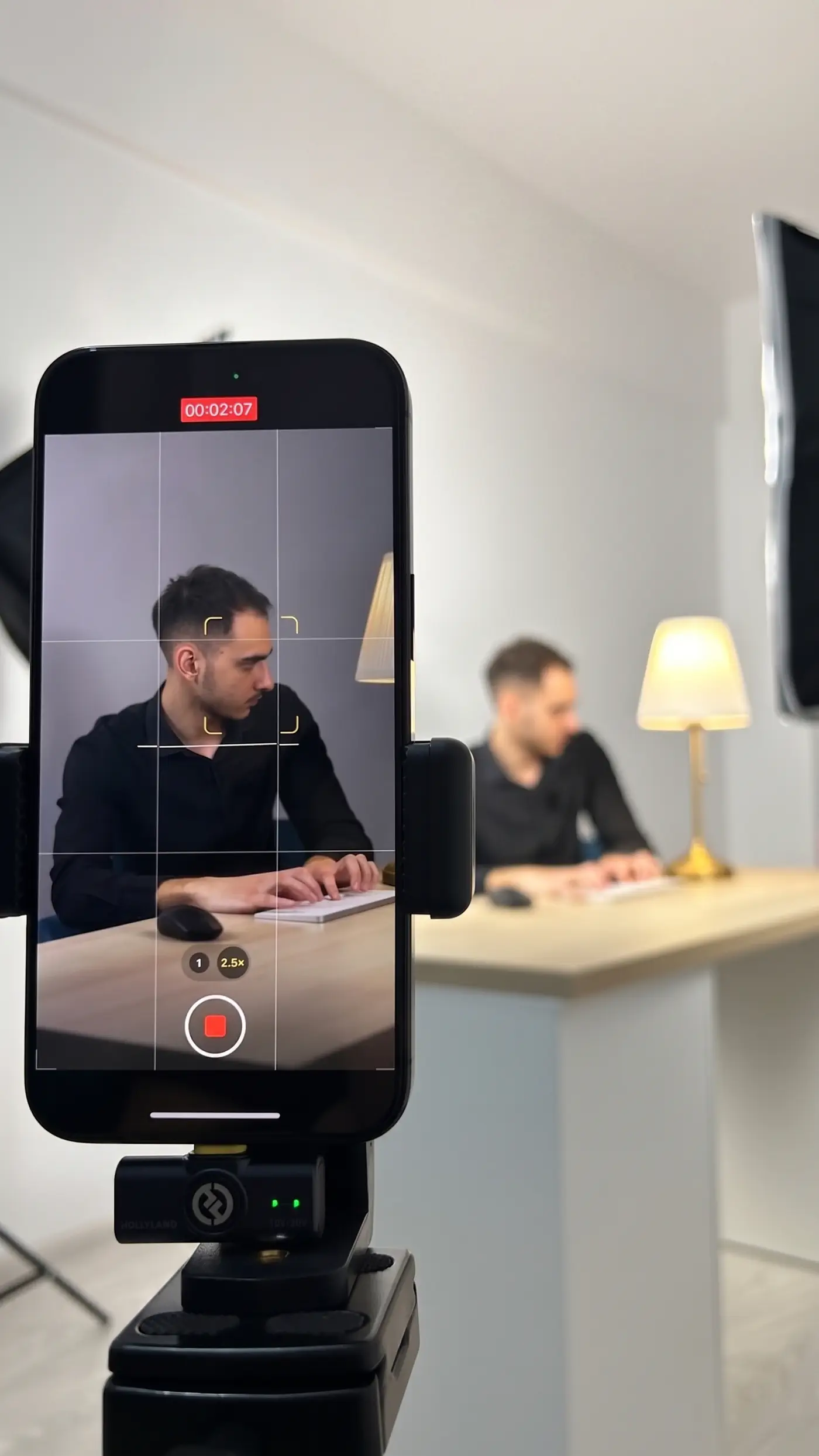 A phone on a tripod with a wireless microphone, recording a Vasonim team member at his desk
